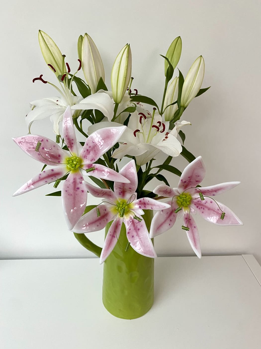 Pink and white lilies in a green glass vase